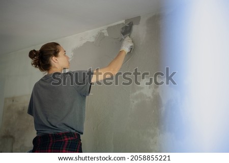 Young woman doing home repairs by applying plaster using a trowel Photo stock © 