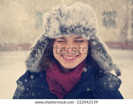 cute funny happy  girl in a fur cap  laughing under the snow, image with instagram retro effect