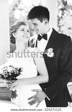attractive bride and groom kissing, sitting on a bench, black and white image