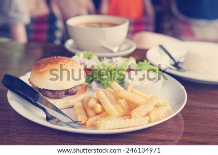 classic burger with French fries on the table in a cafe. Retro toning