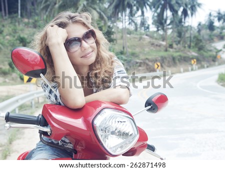 beautiful young woman on a red motorbike on the road