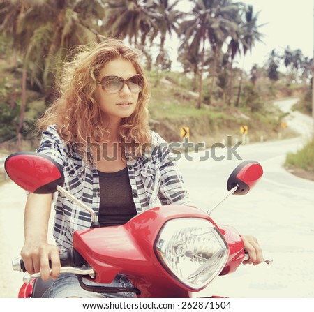 beautiful young woman on a red motorbike on the road