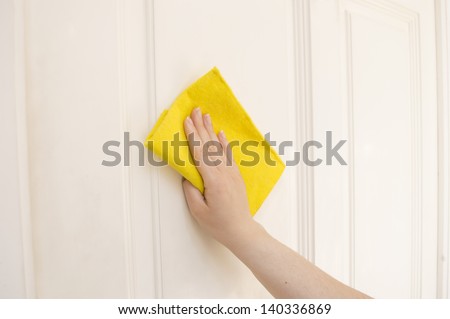 hand cleaning a white door with a yellow cloth