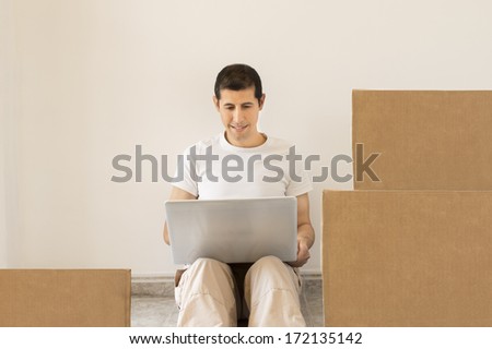 man sitting on the floor looking for a moving company online