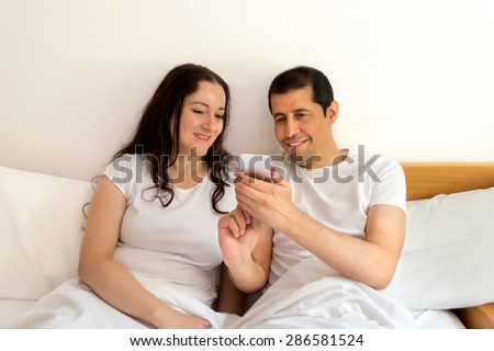 couple in bed surfing the net with your smart phone in the bedroom