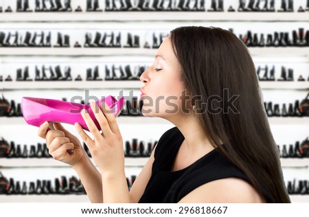 Attractive woman giving a kiss pink heeled shoes in the shoe store