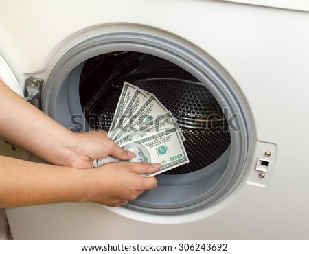 hand putting dollar money into the laundry machine in concept crime of Money Laundry