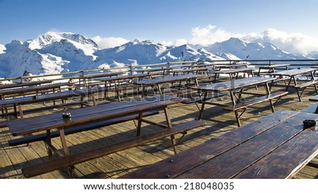 Outdoor terrace of a mountain restaurant in the Alps, snowy peaks in the background