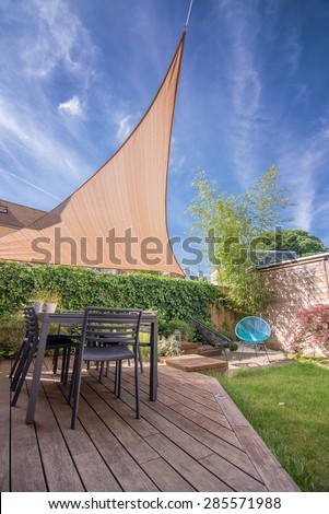 Modern house terrace in summer with table and shade sail