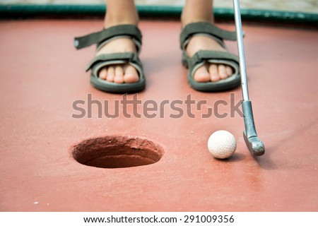 Close up on the feet of a kid playing mini golf