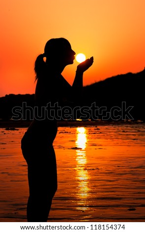 Silhouette of a girl kissing the sun at sunset.