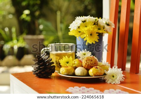 teatime with Chinese pastry and tea and flower on a orange chair
