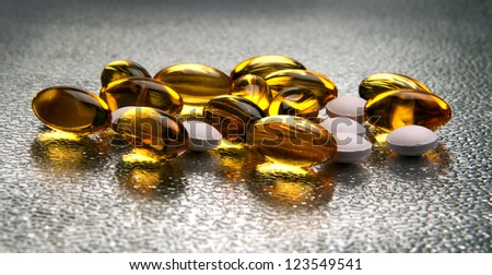 Closeup of vitamin E and vitamin D capsules on metallic background