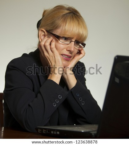 Stressed female executive office with hands on face looking at computer