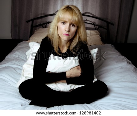 Depressed woman sits on bed