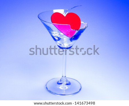 Concept photo of broken relationship with heart sitting in broken martini glass shot on light table with blue light