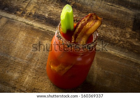 Two mason jar Bloody Mary or Caesar  with  bacon on wood background