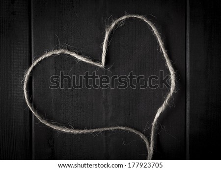 Closeup of hemp twine or string in shape of a heart on dark wood
