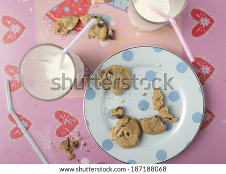 Messy table from children\'s party with milk spilled and cookies