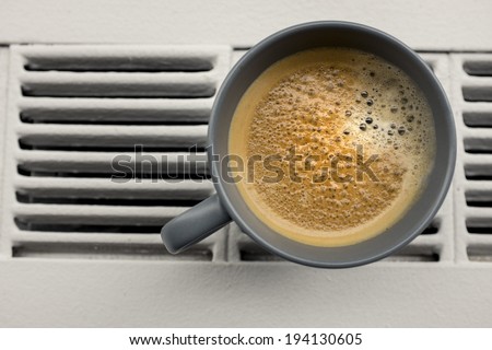 Espresso coffee cup sits on window ledge radiator in office building