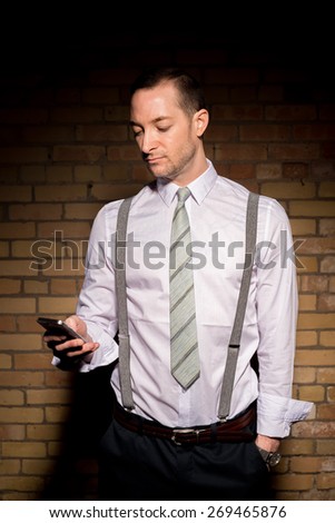 Portrait of a man in tie with beard stubble. Checking cellphone.