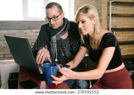 Entrepreneur couple discuss business in their office while looking at laptop  computer
