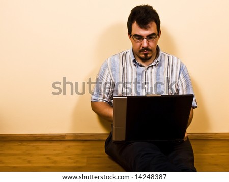 young man sit down on bamboo floor work with his laptop 01