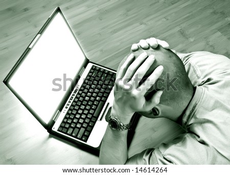 man lying down on bamboo floor having problems with his laptop