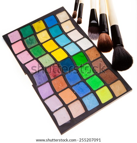 Set of powder eye shadows in jars and brushes on white background