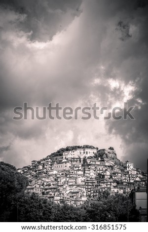 artistic black and white edit with vignette of a town on a hill, and a cloudy sky, with copy space for text