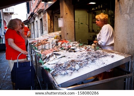 VENICE - SEPTEMBER 4: Woman shops in fish market on September 4, 2013 in Venice. Traditional markets provide daily supplies of fish, vegetables or fruits since 1097.