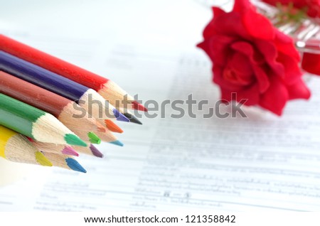 Colorful pencils and rose on paper