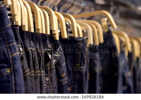 Many blue denim jeans on coat hanger