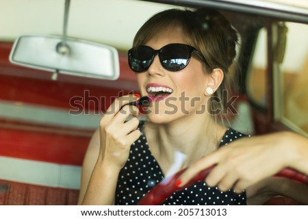 Pretty girl in a car. Cute blond woman applying lipstick in a car