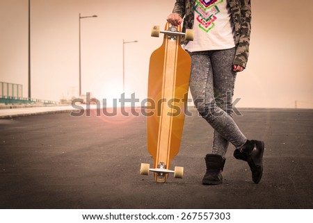 Beautiful and fashion young woman posing with a skateboard .Lens flare