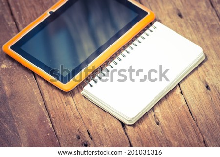Notebook paper with Tablet on wooden