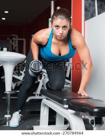 girl doing exercise with dumbbells in fitness room. Attractive fitness woman, trained female body, lifestyle portrait, caucasian model. Fitness theme.