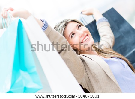 Excited shopping woman with arms up holding bags