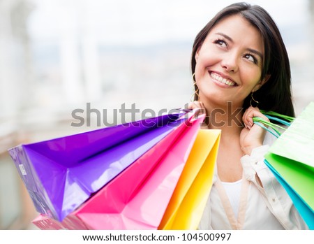 Thoughtful woman holding shopping bags and looking up