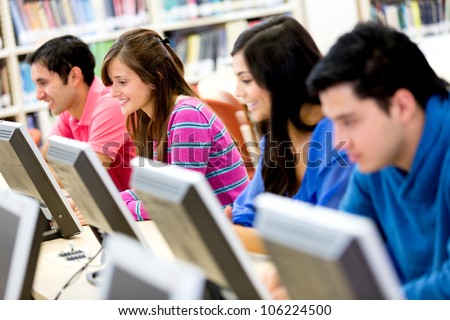 Group of young people studying at the library using computers