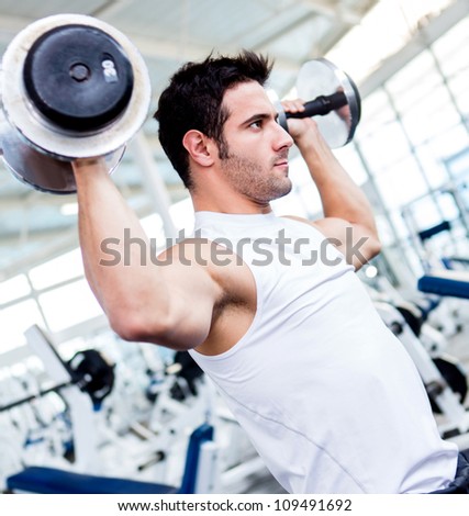 Handsome gym man lifting heavy free weights