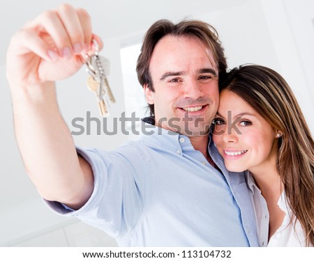Couple holding keys to their house and looking very happy