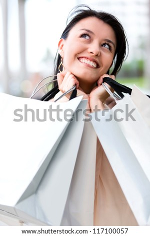 Thoughtful female shopper looking happy carrying shopping bags