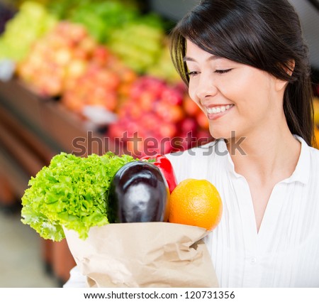 Latin woman grocery shopping looking very happy