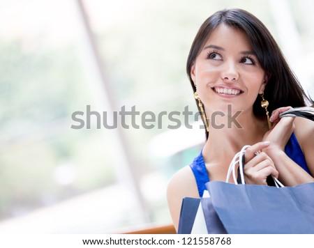 Thoughtful shopping woman holding bags and smiling