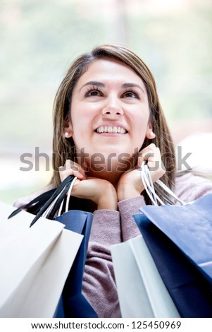 Thoughtful female shopper holding shopping bags
