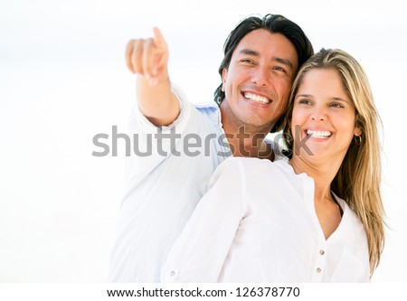 Happy loving couple outdoors pointing away
