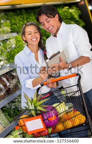 Couple with shopping list on a tablet computer at the supermarket