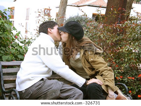 couple kissing on a bench