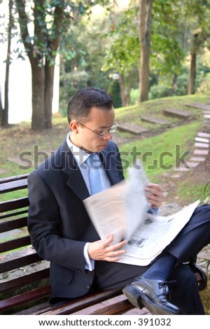 business man reading newspaper on a bench